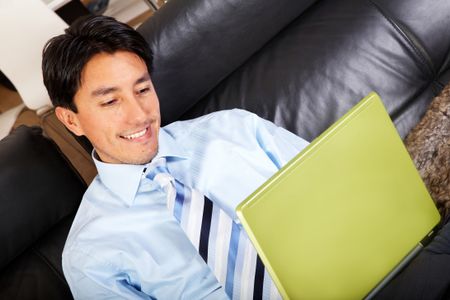 business man on a laptop computer browsing the internet at home comfortably sitting in his sofa