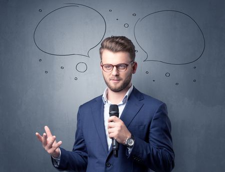 Businessman speaking into microphone with speech bubbles over his head