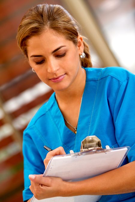 Female doctor writing on a clipboard at the hospital