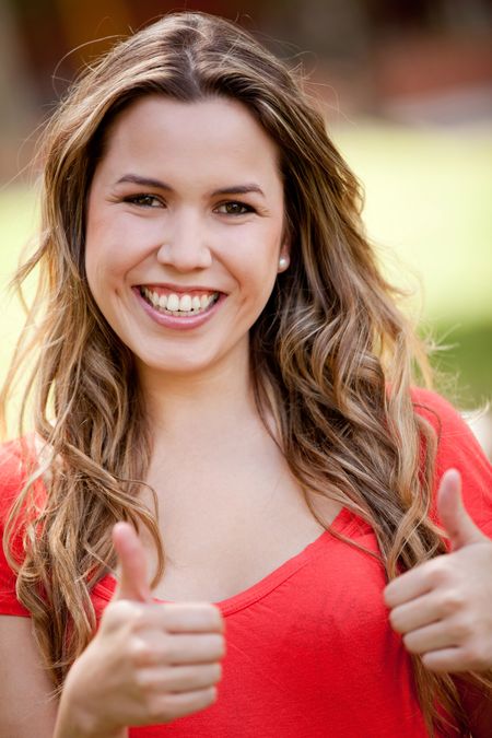 Portrait of a lovely woman with thumbs up outdoors