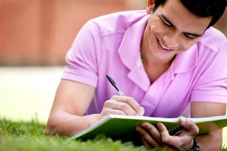 Casual man studying outdoors lying on the floor