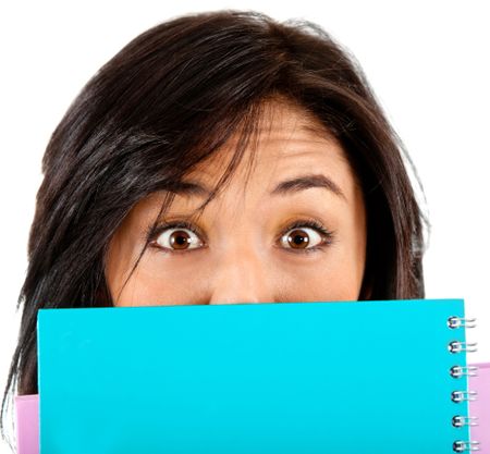 Surprised female student covering her face with a notebook - isolated
