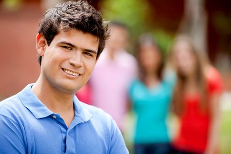 Casual man smiling outdoors with a group behind him