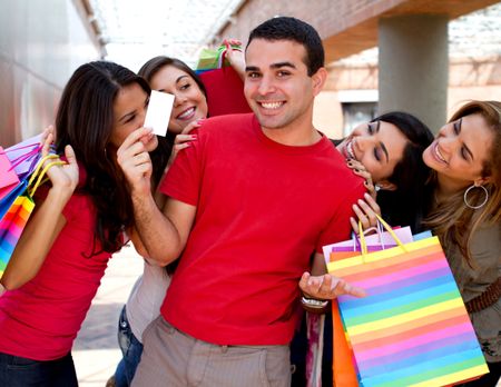 Group of happy shopping people and a man holding a credit card