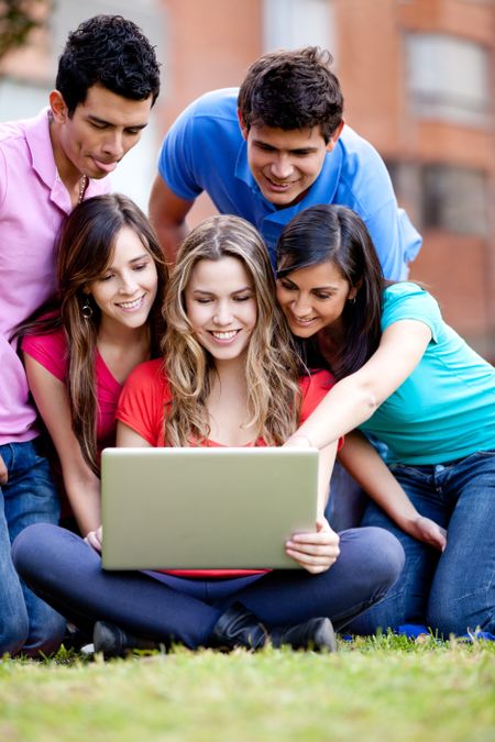 Surprised group of friends looking at a laptop outdoors