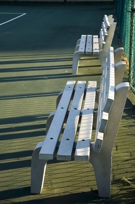 Two white benches by tennis court