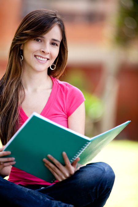 Happy female student carrying notebooks outdoors