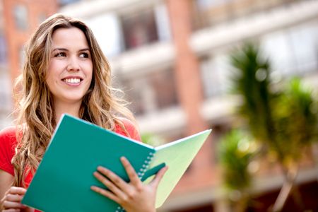 Portrait of a woman studying outdoors with a notebook