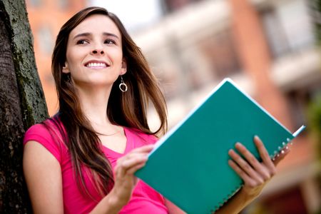 Pensive female student with a notebook outdoors