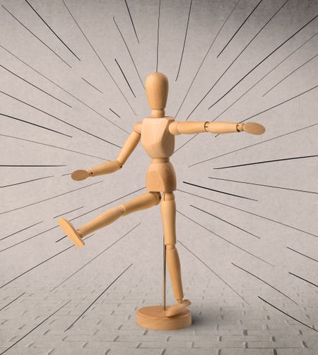 Wooden mannequin posed in front of a greyish background with black lines around him