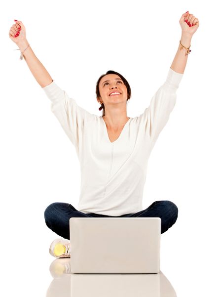 Woman sitting on the floor with a laptop computer and arms up - isolated