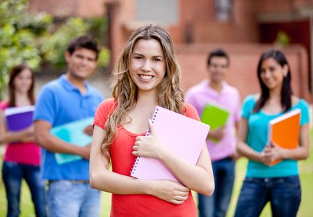Female student smiling with a group behind ? outdoors