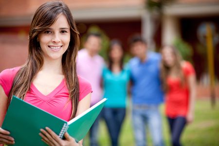 Female student carrying notebooks outdoors and smiling