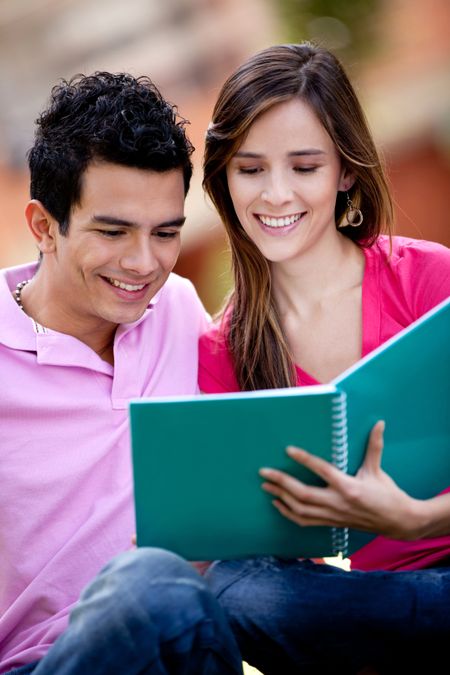 Couple of students with a notebook outdoors