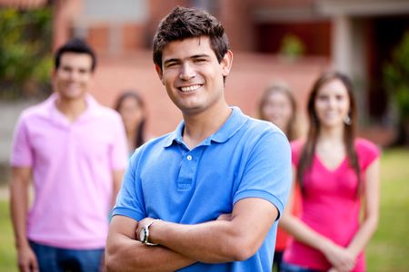 Casual man smiling outdoors with a group behind him
