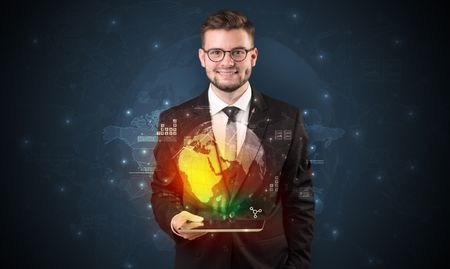 Spectacled businessman with global hologram concept and tablet on his hand
