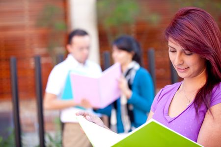 female-student-carrying-notebooks-outdoors-smiling-76333177 Female student carrying notebooks outdoors and smiling