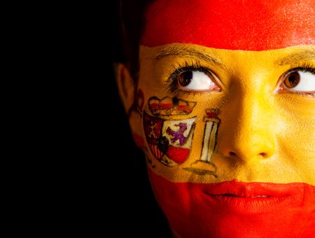 Pensive Spanish woman with the flag painted on her face ? isolated over a black background