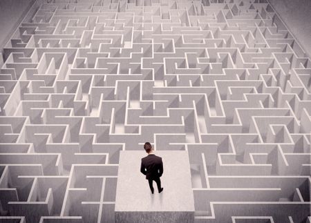 A confused businessman thinking while standing on a square platform above a detailed maze