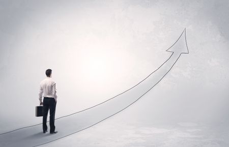 Adult elegant male with briefcase standing on drawn grey arrow pointing up financial concept