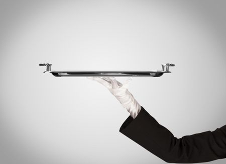 An elegant waiter business hand in white glove holding an empty plate with grey blank gradient background.