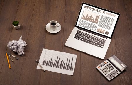 Business laptop with stock market report on wooden desk and accessories