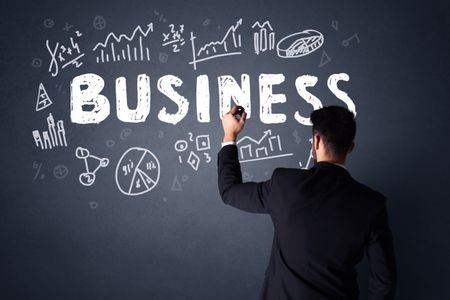 Young businessman in black suit standing in front of a detailed business plan 