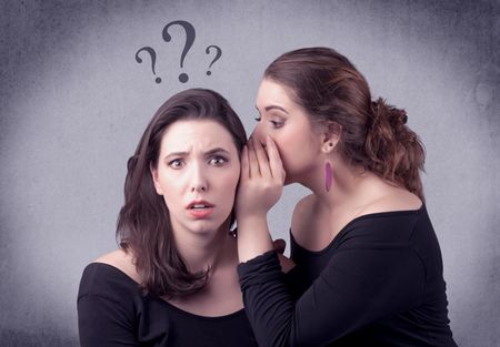 A teenager girl looking confused with drawn question marks above the head, while a girlfriend whispers something in her ear concept.