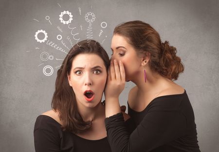 Two girlfriends in elegant black dress sharing secrets with each other concept with drawn rack cog wheels and spiral lines on the wall background.