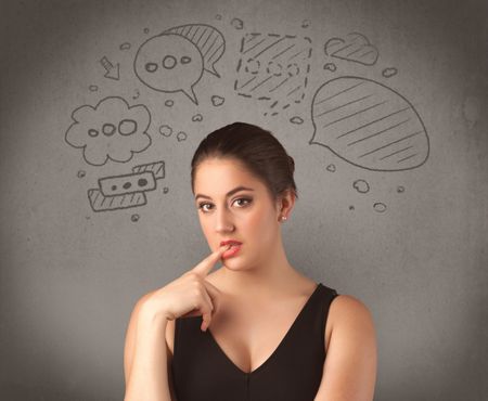 A cute female student making funny expressions with thoughts in her head illustrated by drawn chat bubbles on the urban wall background concept.