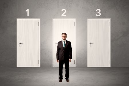 Businessman in grey room with three numbered white  door behind his back
