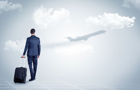 Young businessman with luggage walking towards an looking to a raising airplane
