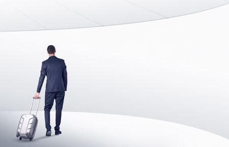 Businessman with back walking in a white waiting room with empty walls around
