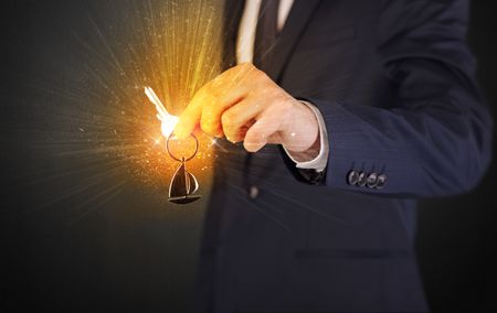 Formal man hand over shiny keys with dark background
