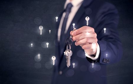 Businessman in suit holding keys with keys graphics around and dark background
