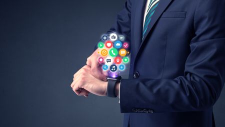 Businessman wearing smartwatch with colored application symbols on it.