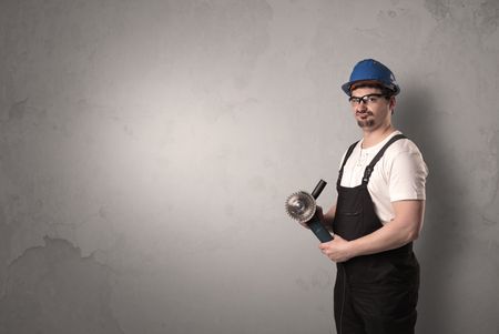 Craftsman standing in front of an empty wall with tool in his hand.