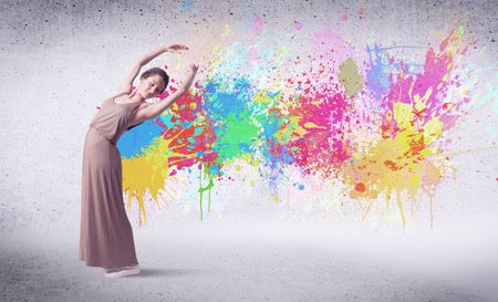 Modern street dancer jumping with colorful paint splashes on back wall concept