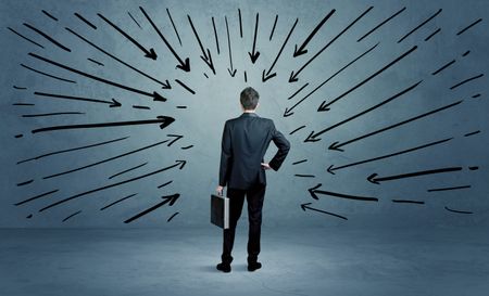 confused-businessman-pressur-making-bad-decision-773556274 A confused businessman under pressur after making a bad decision illustrated with drawn arrows pointing at him in clear blue urban space concept