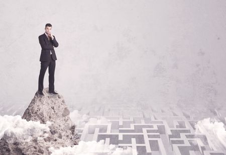 Maze is no challenge for successful businessman standing on top of a cliff as he is the best at solving problems concept