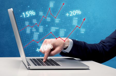 An elegant businessman working on graph statistics calculation using a laptop with clear blue background concept