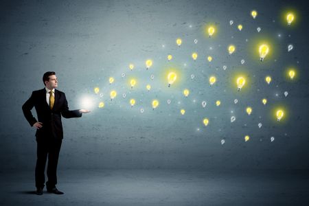 Caucasian businessman holding lightbulbs which are flying out from his hands