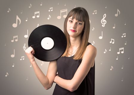 Young lady holding vinyl record on a brown background with musical notes behind her