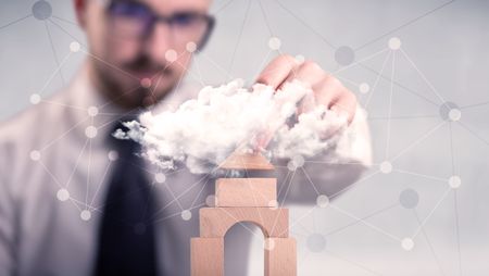 Young handsome businessman using wooden building blocks behind cloud concept 
