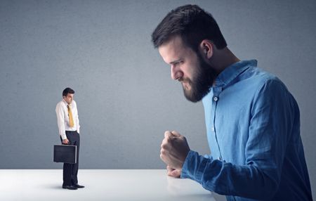 Young professional businessman being angry with an other miniature businessman 