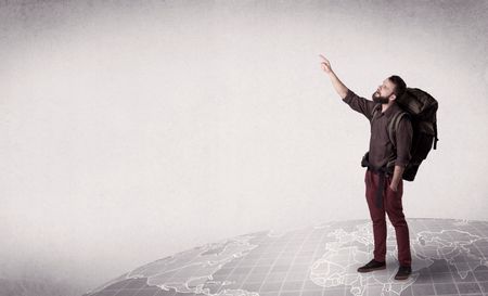 Handsome young man with a backpack on his back standing on a world map