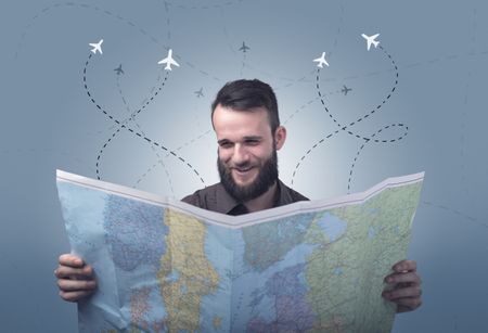 Handsome young man holding a map with little planes and their paths above him 