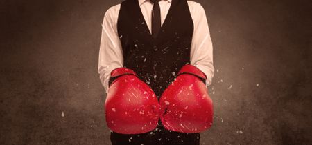 A strong sales person breaking something into pieces with red boxing gloves concept illustrated with glowing residue flying in the air.