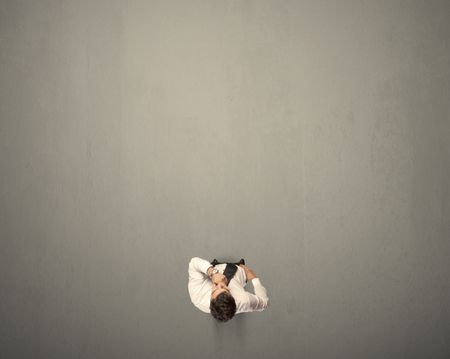 Young businessman contemplating a decision standing on a grey surface