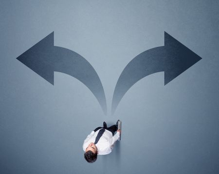 Young smart businessman standing in front of two arrows potinting to different ways contemplating a decision 